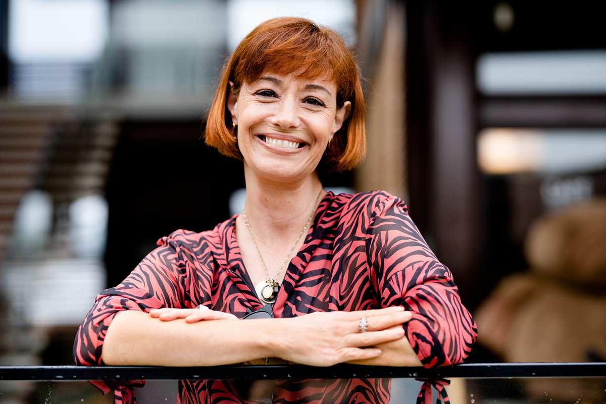 kobieta  w wieku około 45 lat rude włosy w kolorowej sukience w zebrę uśmiecha się szeroko