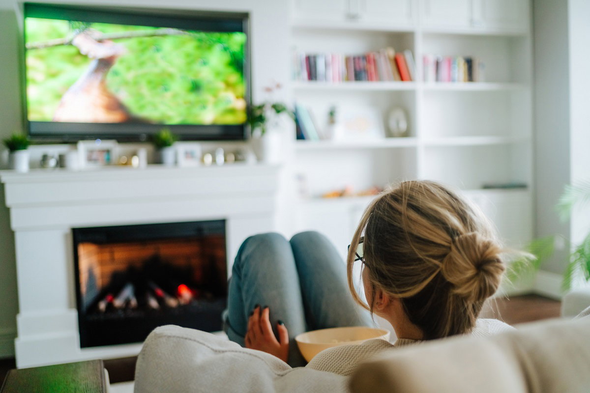 Video TV streaming service. Woman eating popcorn and watching tv at home