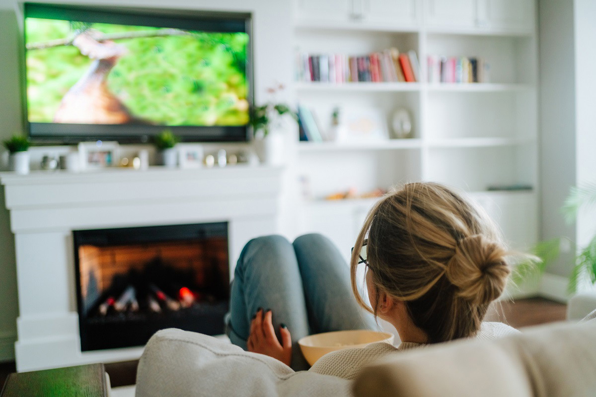Video TV streaming service. Woman eating popcorn and watching tv at home