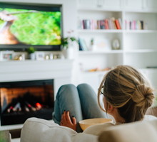 Video TV streaming service. Woman eating popcorn and watching tv at home