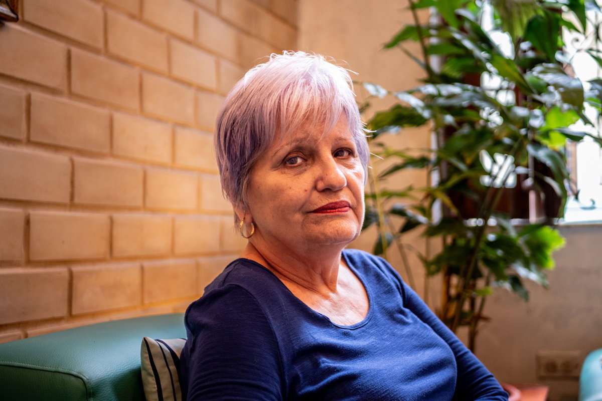 kobieta w wieku około 70 plus z krótkimi włosami siedzi smutna w salonie