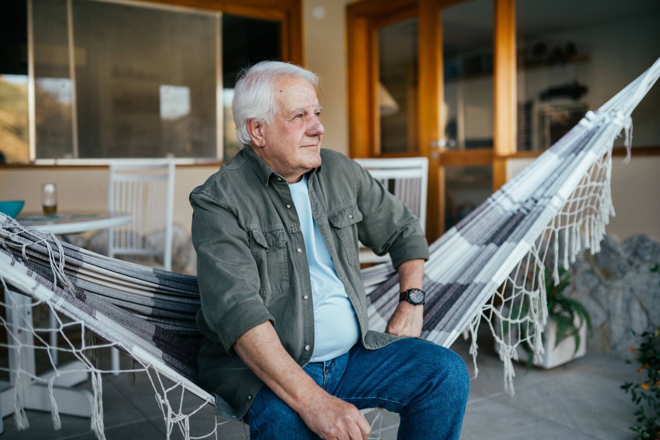 Senior man sitting on a hammock and looking forward