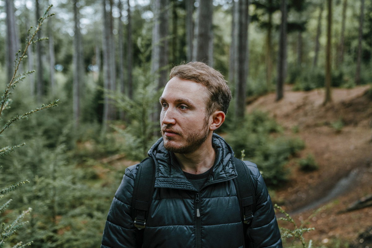 mężczyzna w wieku około 30 lat stoi w lesie z niepewna miną