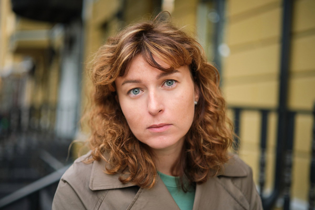 kobieta w wieku 40 plus z kręconymi włosami stoi na ulicy w płaszczu smutna