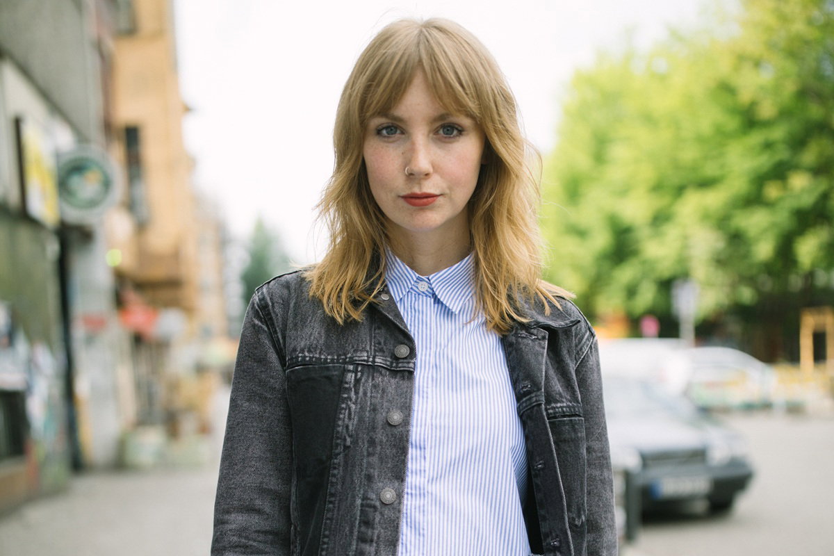 młoda kobieta w wieku około 25 plus blondynka stoi na ulicy i patrzy poważnym wzrokiem