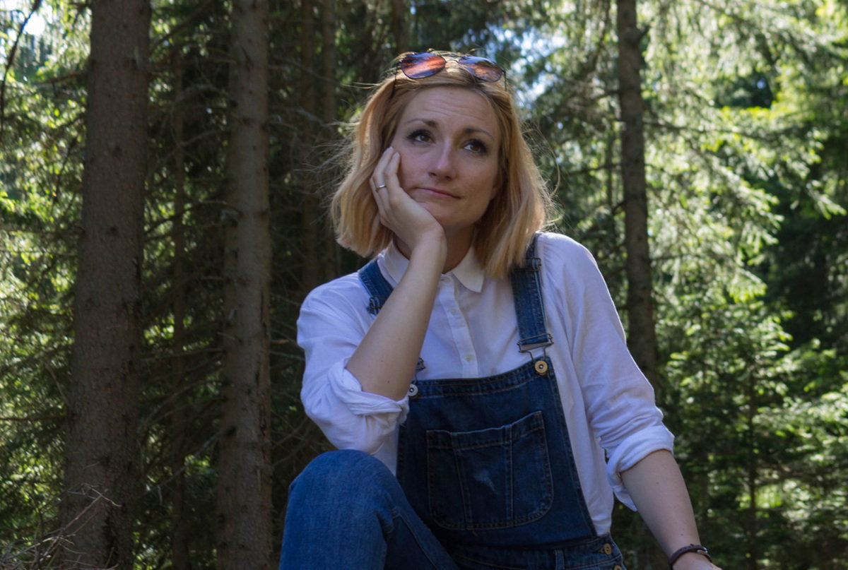 kobieta 30 plus blondynka siedzi na pniu w lesie i rozmyśla