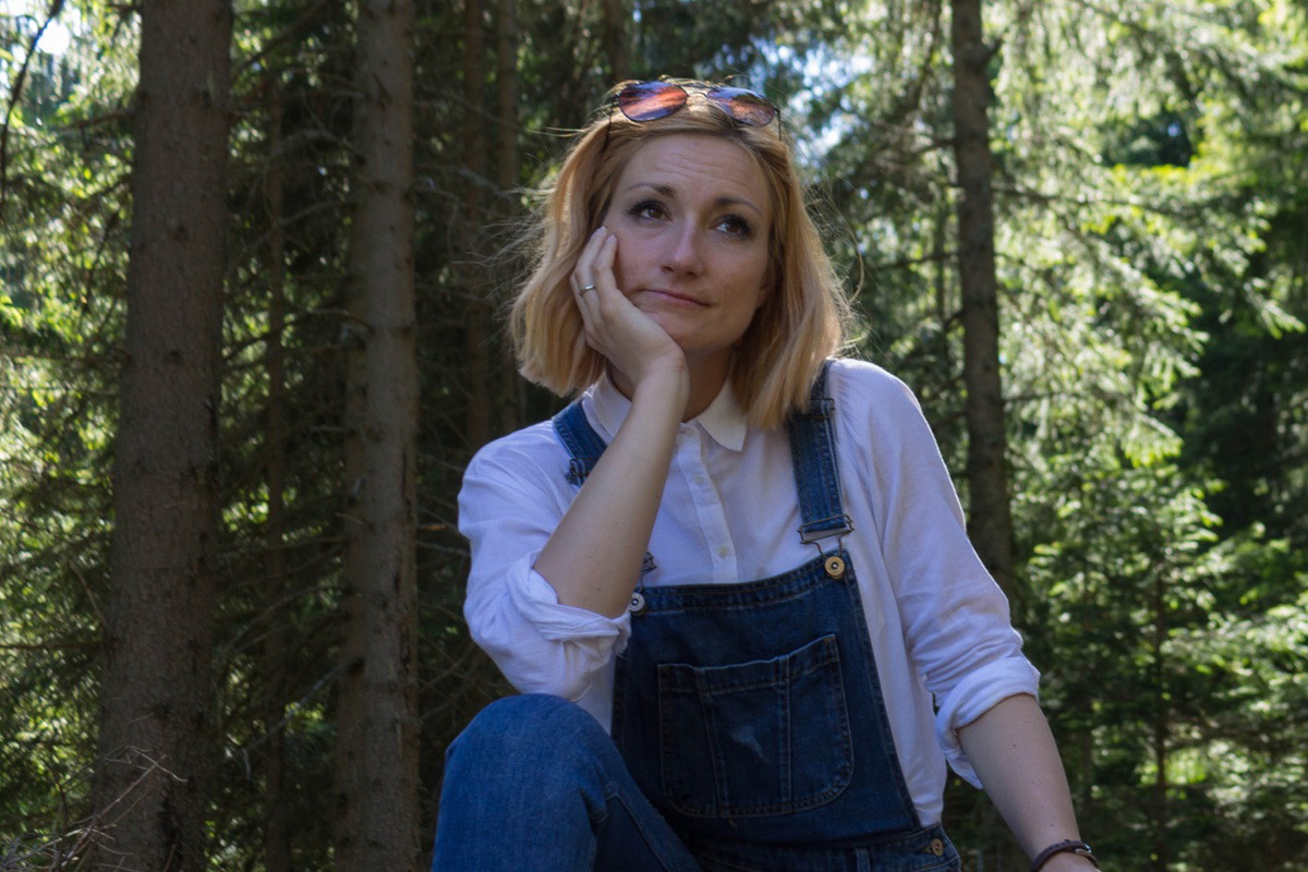 kobieta 30 plus blondynka siedzi na pniu w lesie i rozmyśla