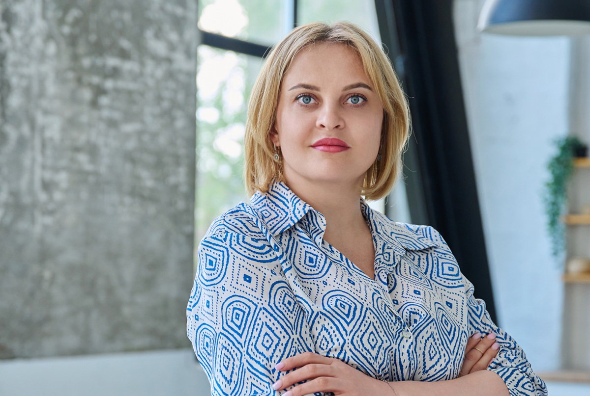 kobieta 35 plus blondynka stoi w kuchni z lekko zdziwioną miną i skrzyżowanymi rękami