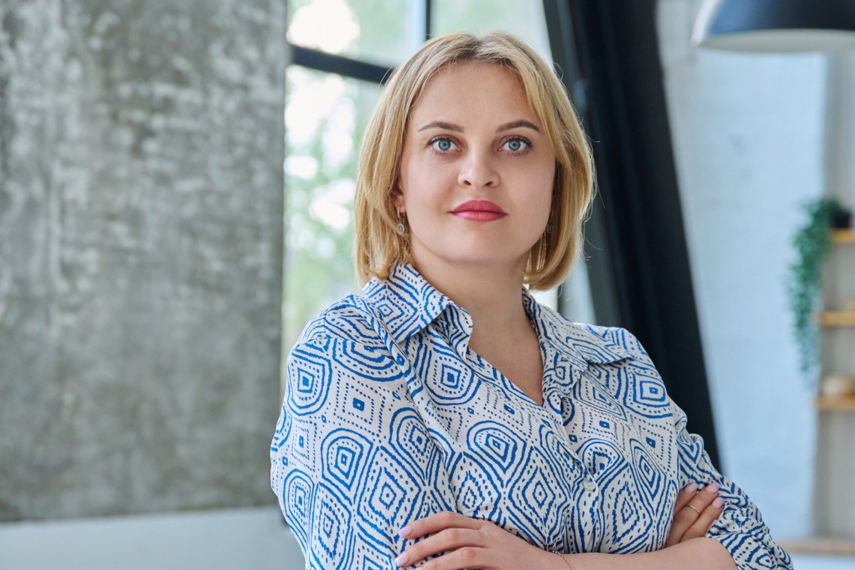 kobieta 35 plus blondynka stoi w kuchni z lekko zdziwioną miną i skrzyżowanymi rękami