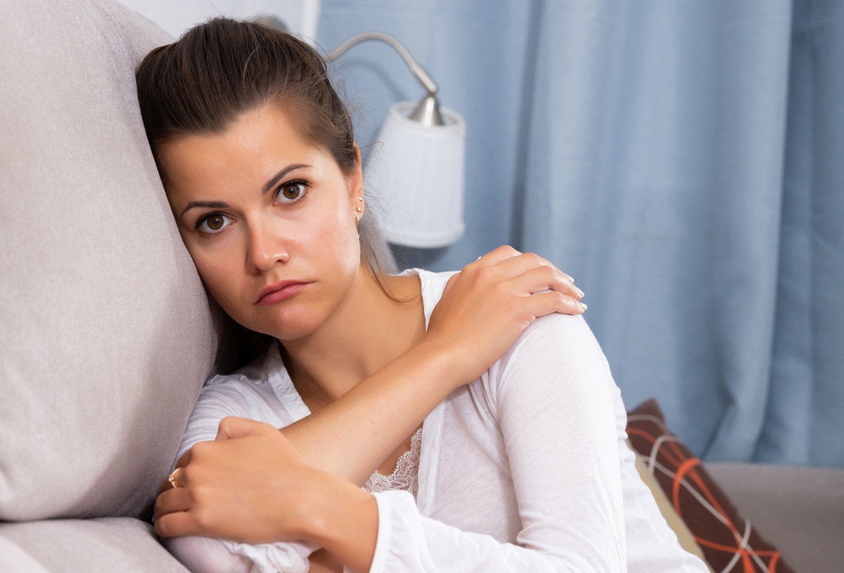 kobieta w wieku 30 plus siedzi na kanapie smutna