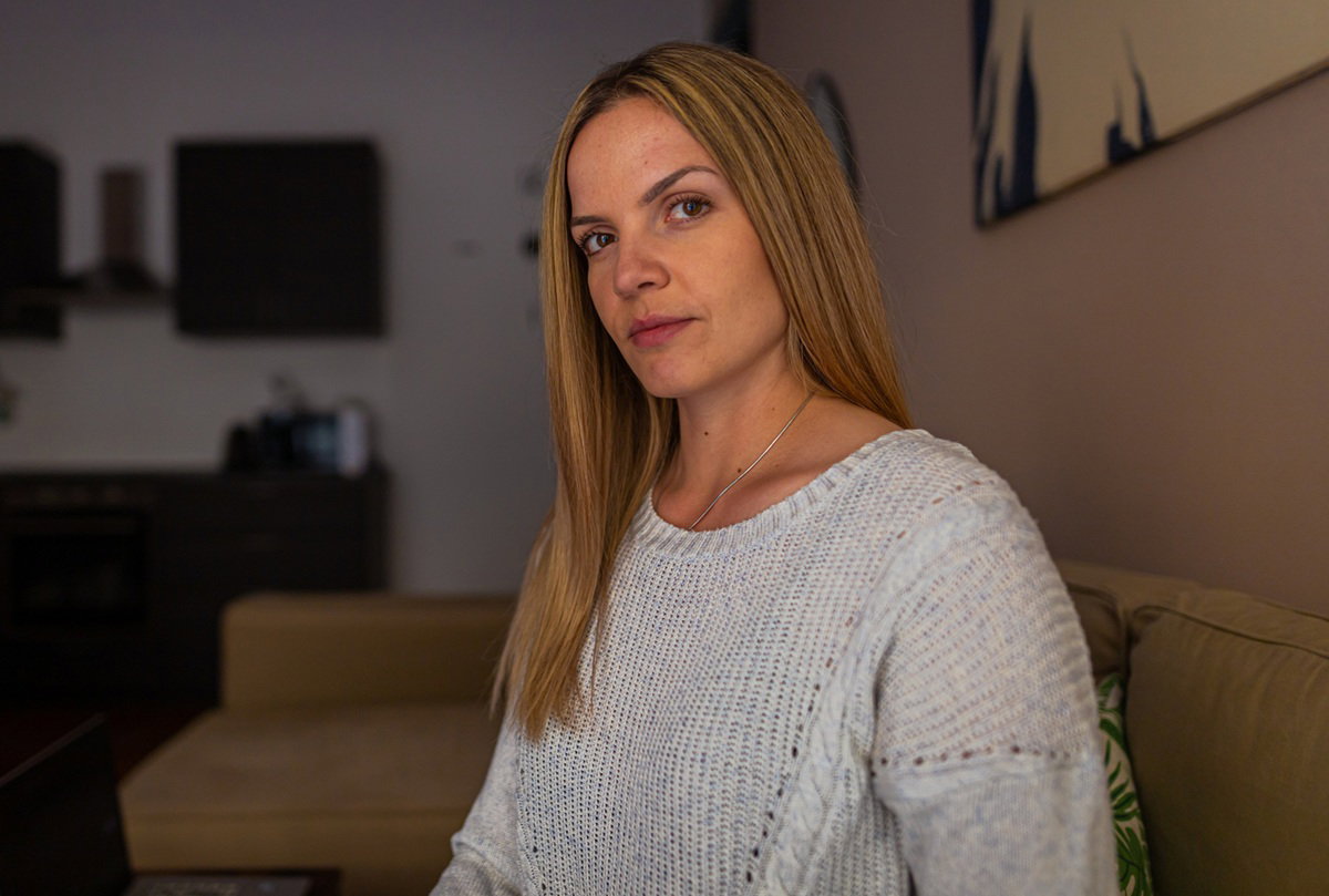 kobieta w wieku 30 plus blondynka z długimi włosami siedzi w ciemnym salonie i ma poważne spojrzenie