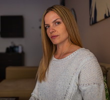 kobieta w wieku 30 plus blondynka z długimi włosami siedzi w ciemnym salonie i ma poważne spojrzenie