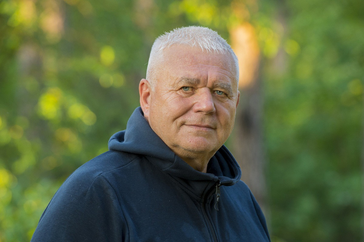 mężczyzna w wieku około 65 plus w bluzie z kapturem stoi na zewnątrz z poważnym spojrzeniem