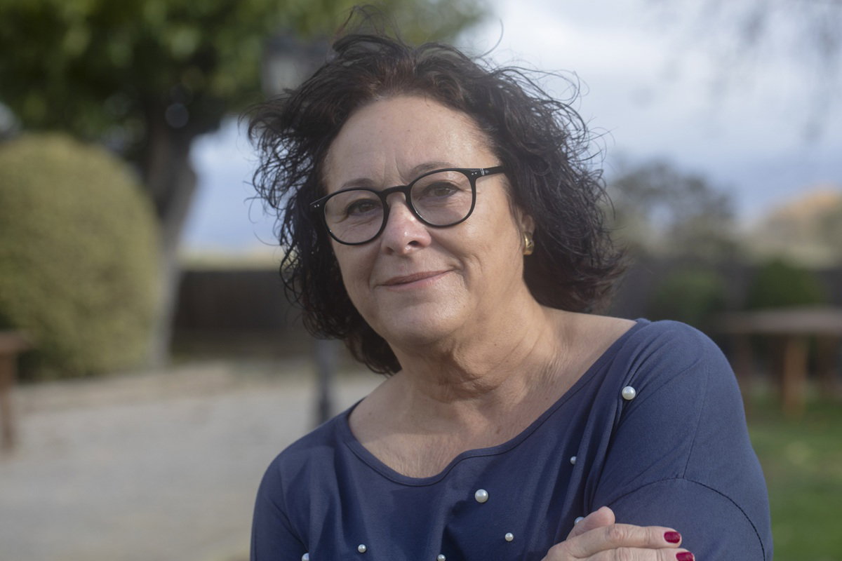 kobieta w wieku 60 plus w okularach stoi na zewnątrz w granatowej bluzce i się uśmiecha