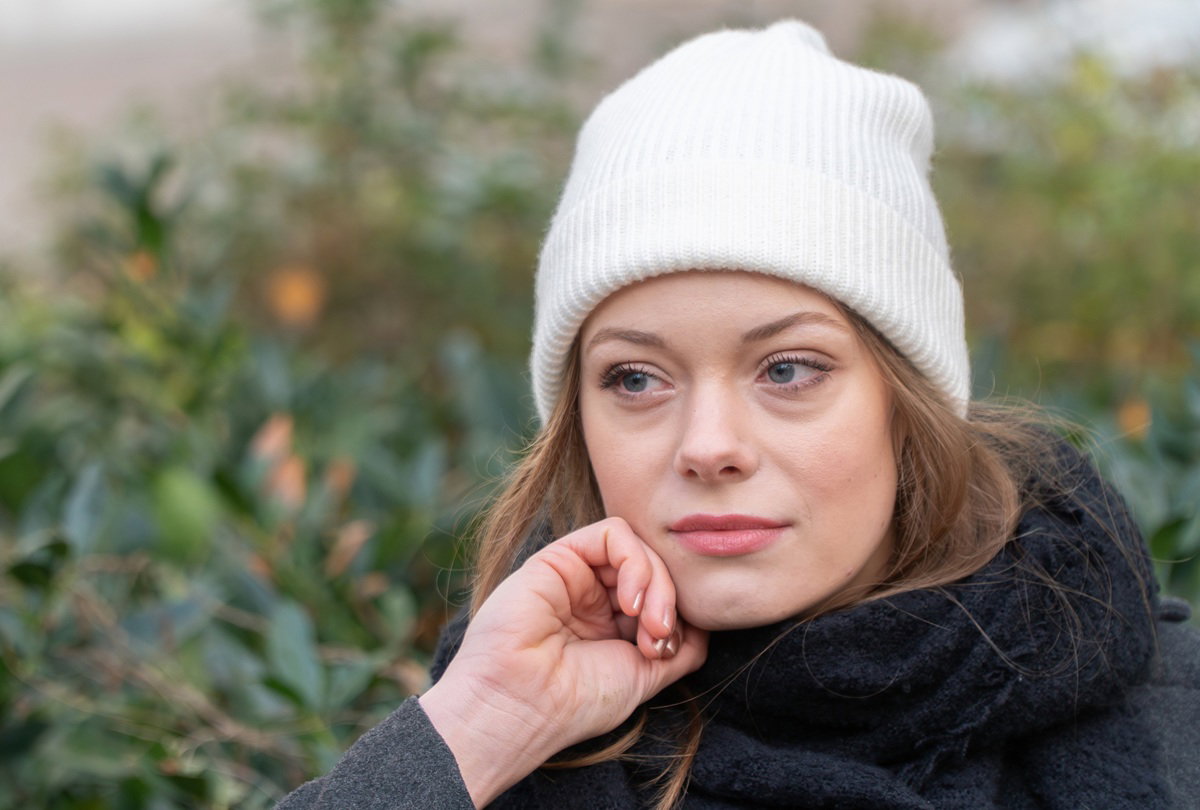 dziewczyna w białej czapce w wieku około 25 plus zamyślona patrzy w dal