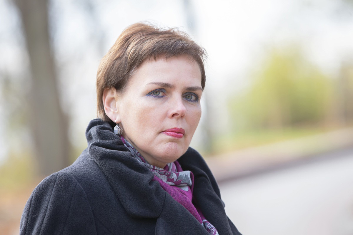 kobieta w wieku 50 plus z krótkimi włosami z grzywką i niebieskim makijażem oczu stoi smutna na zewnątrz
