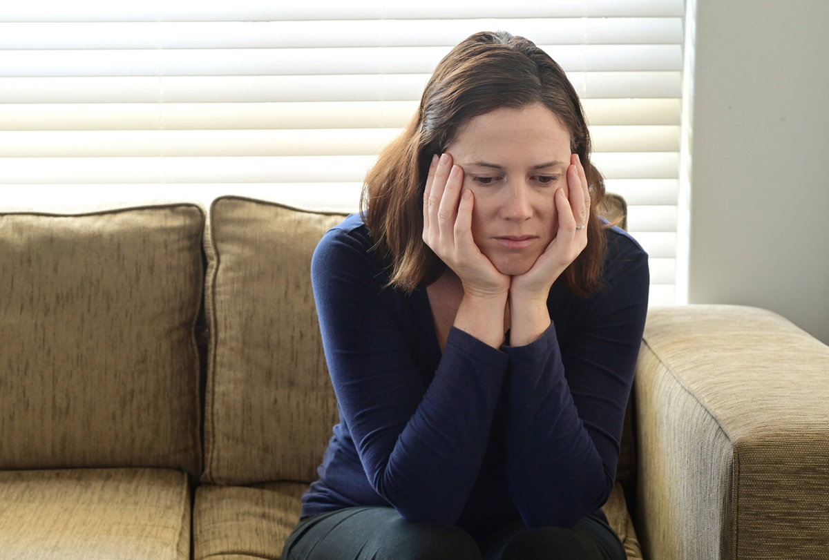 smutna kobieta w wieku 35 plus siedzi na kanapie zamyślona