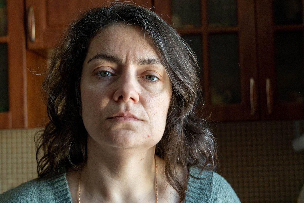 kobieta w wieku 45 plus stoi na tle kuchni smutna i zamyślona