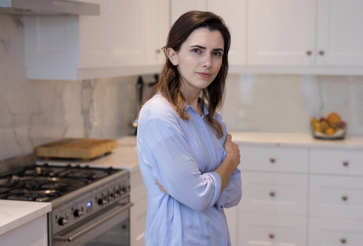 kobieta w wieku około 40 lat w niebieskiej koszuli stoi w kuchni zmartwiona