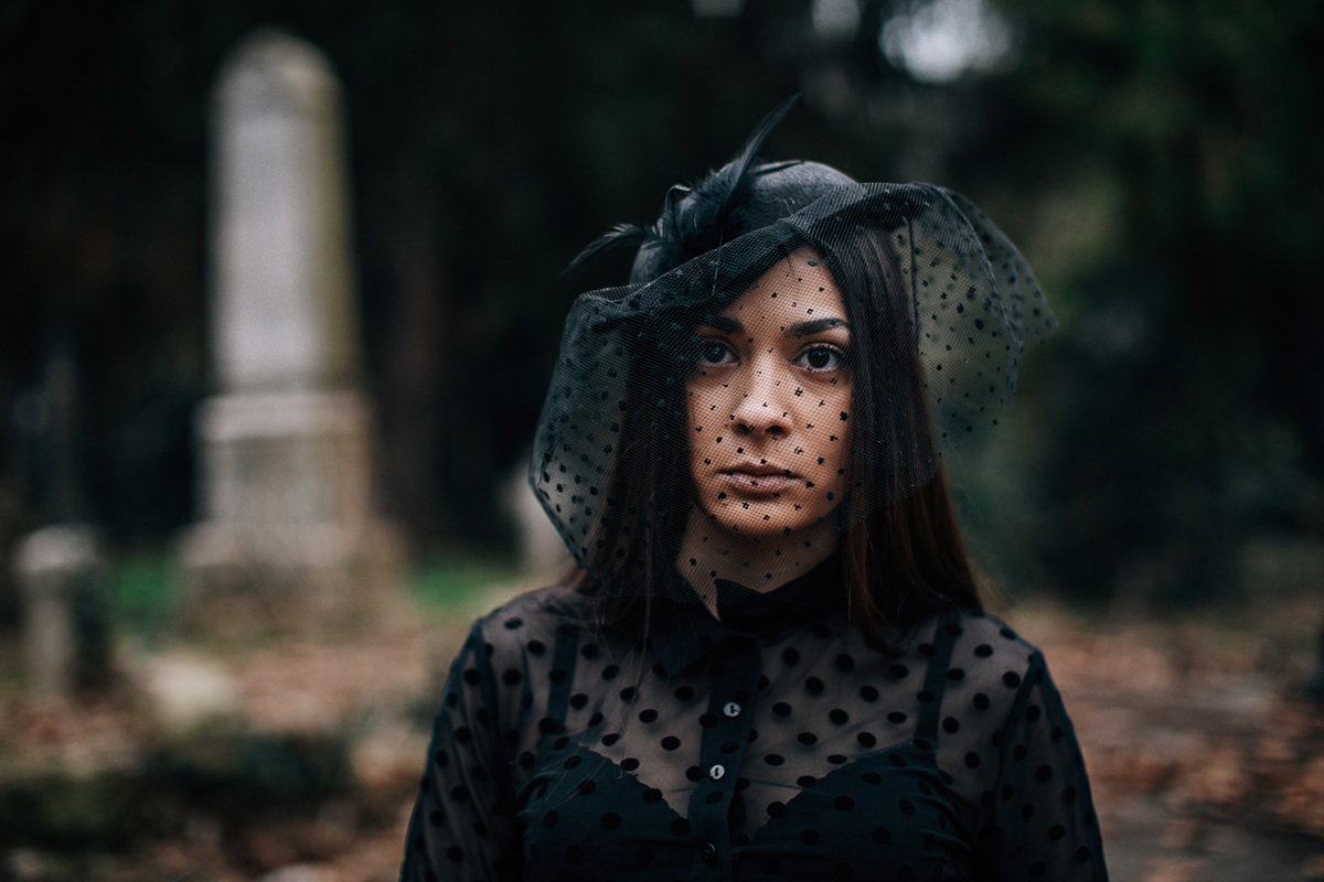 kobieta w wieku 30 plus w czarnej woalce na cmentarzu stoi smutna