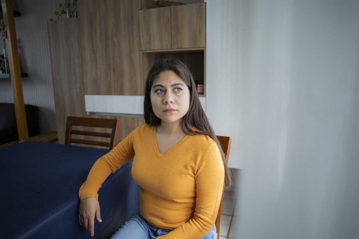 kobieta w wieku około 25 plus w żółtym sweterku siedzi przy stole zamyślona