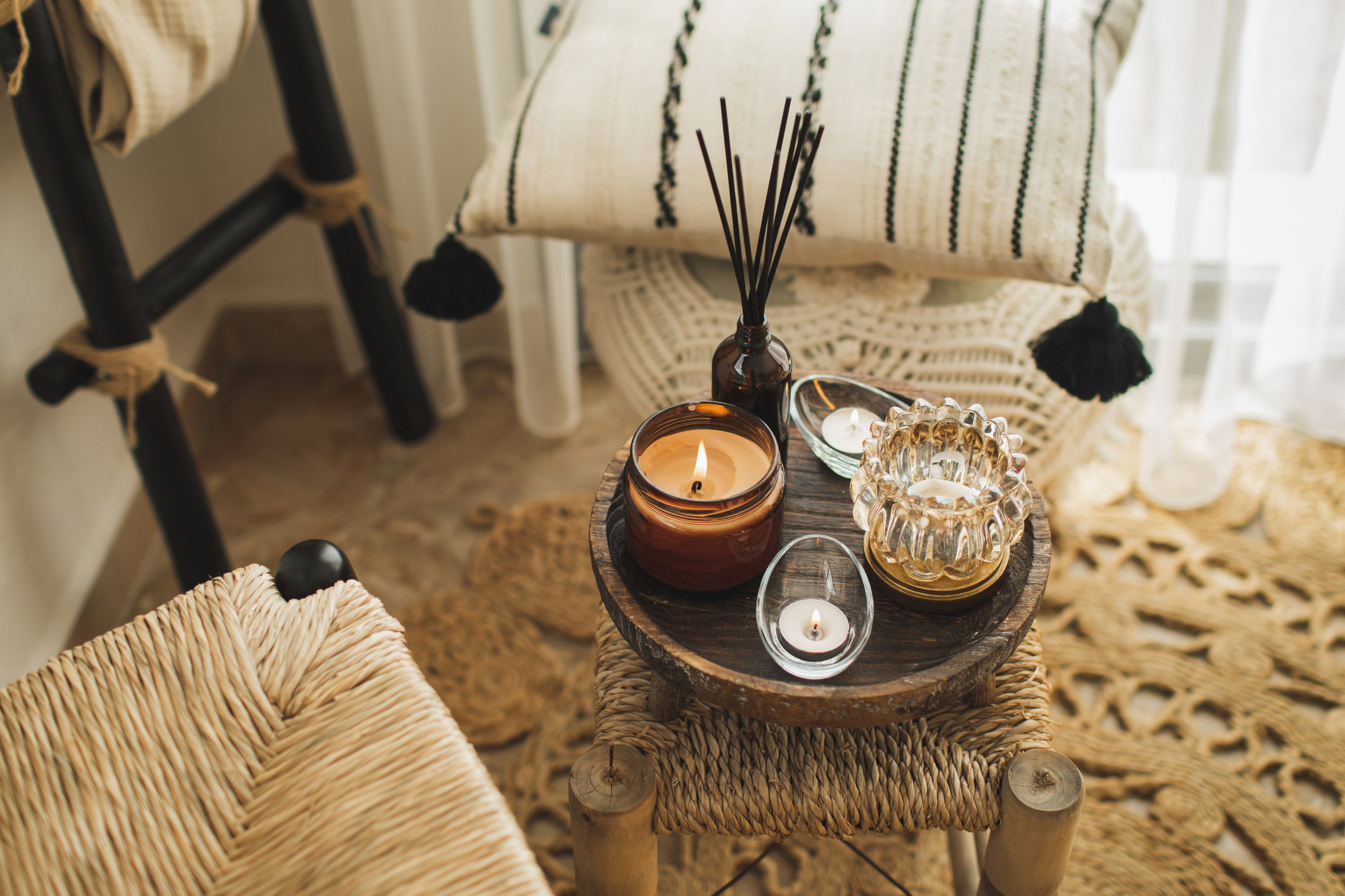 Home decoration with burning candles on wooden coffee table in bright and cozy living room.