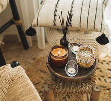 Home decoration with burning candles on wooden coffee table in bright and cozy living room.