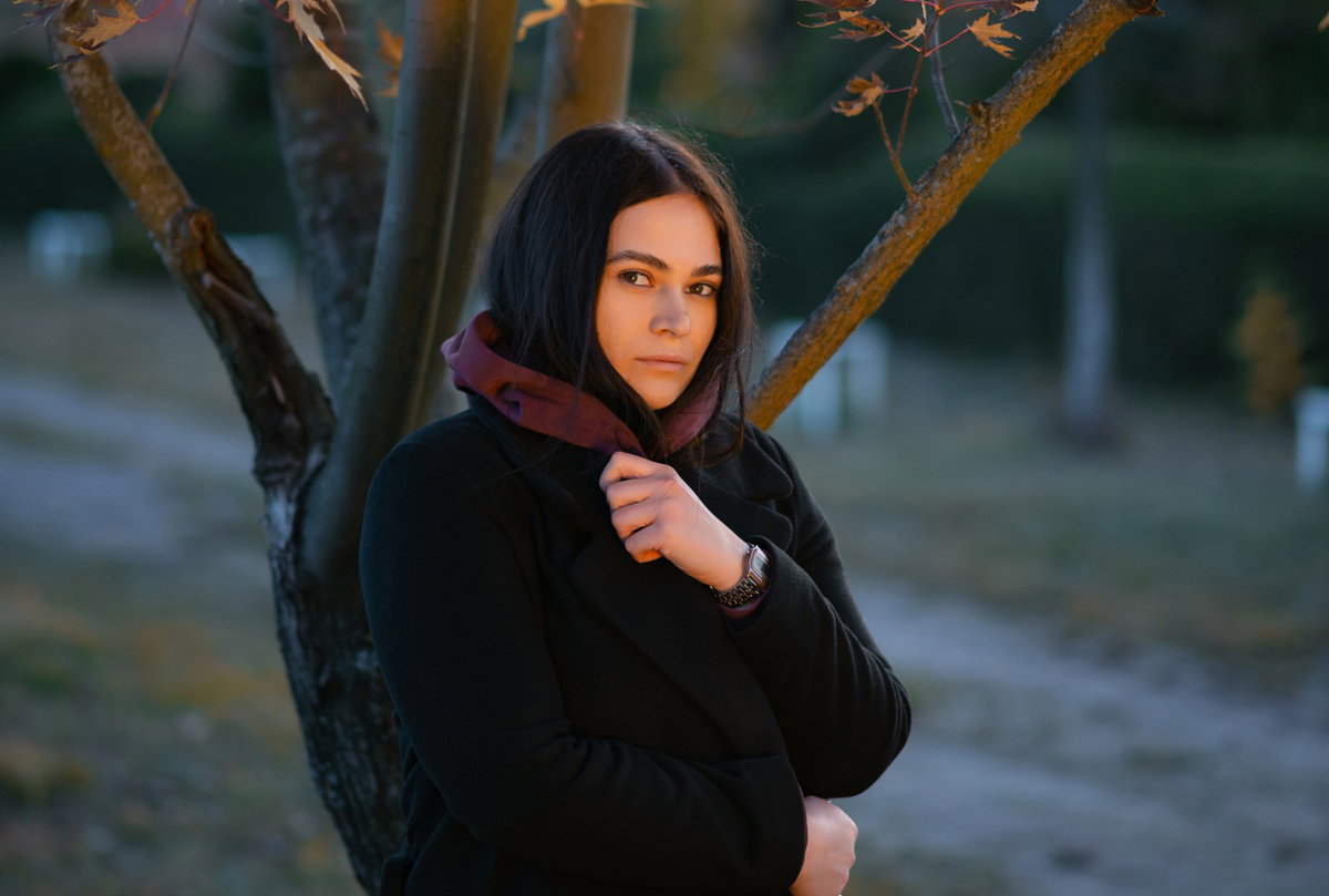 kobieta w wieku około 30 lat w płaszczu stoi na zewnatrz zamyślona i smutna