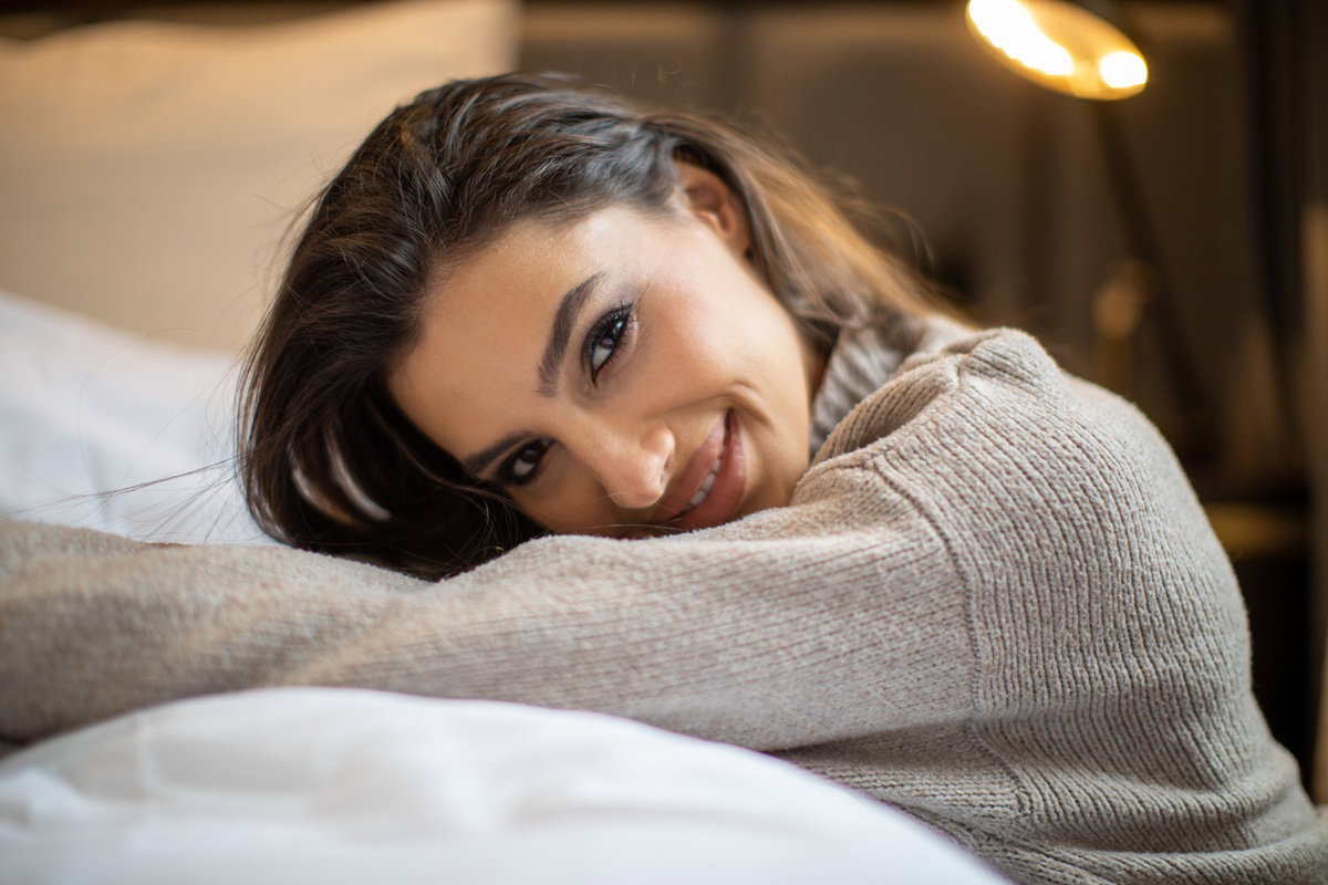 kobieta w wieku 30 plus w sweterku pokłada się i zmysłowo się uśmiecha