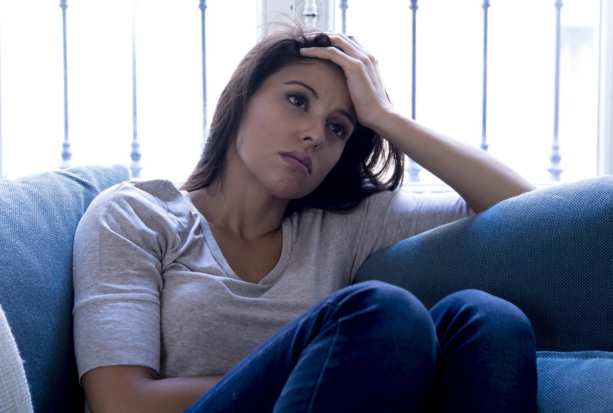 smutna kobieta w wieku 35 plus siedzi na kanapie zamyślona