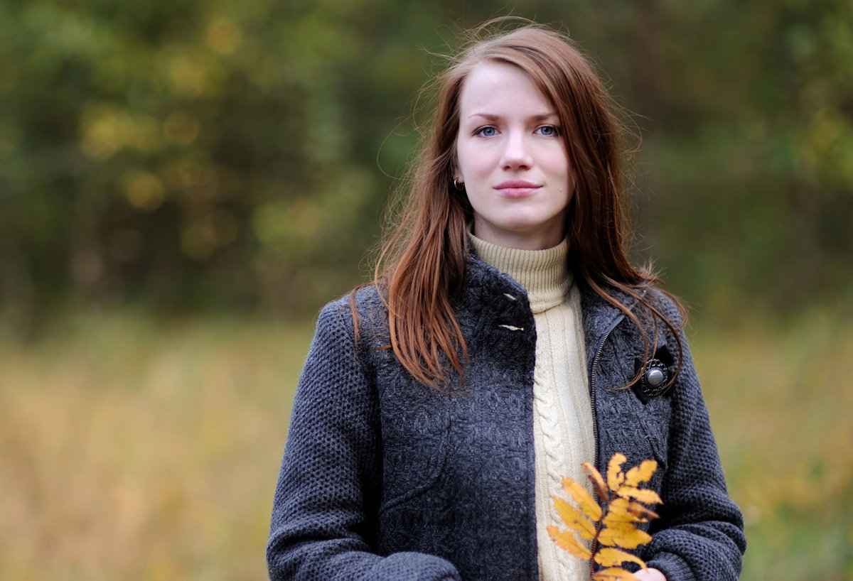 kobieta w wieku 25 plus stoi na łonie natury i trzyma pożółkły listem zamyślona