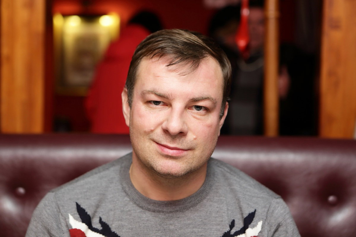 mężczyzna w wieku około 40 lat siedzi lekko smutny i zgorzkniały na kanapie w kawiarni