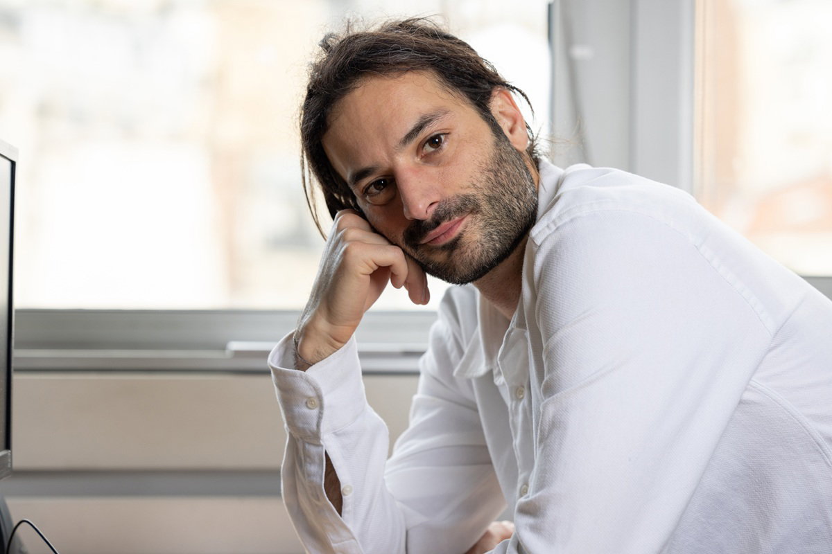mężczyzna w wieku 35 plus w białej koszuli siedzi podpiera się ręką zamyślony i zmartwiony