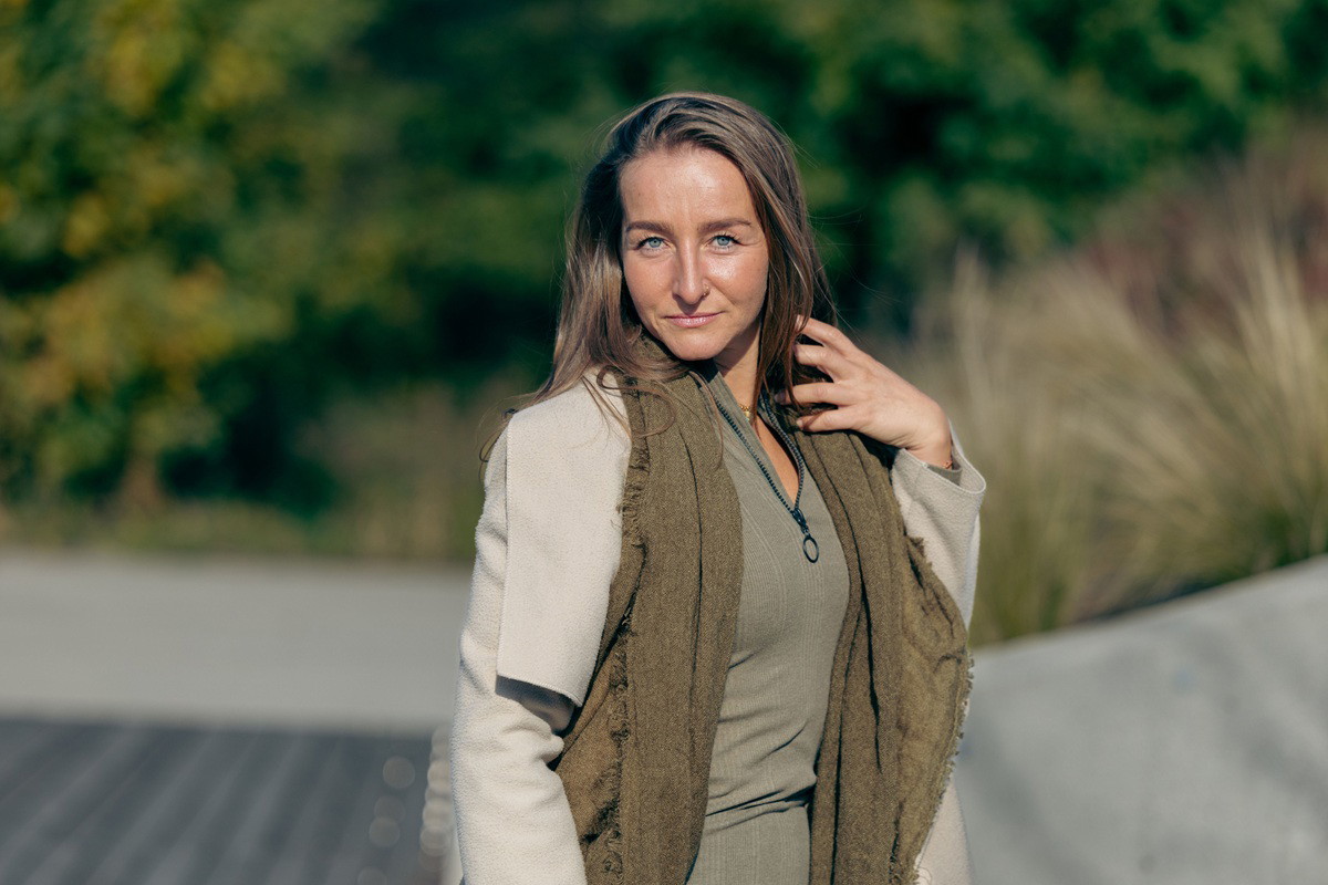 kobieta w wieku 35 plus z jasnymi długimi włosami na zewnątrz patrzy zalotnie stojąc w słońcu