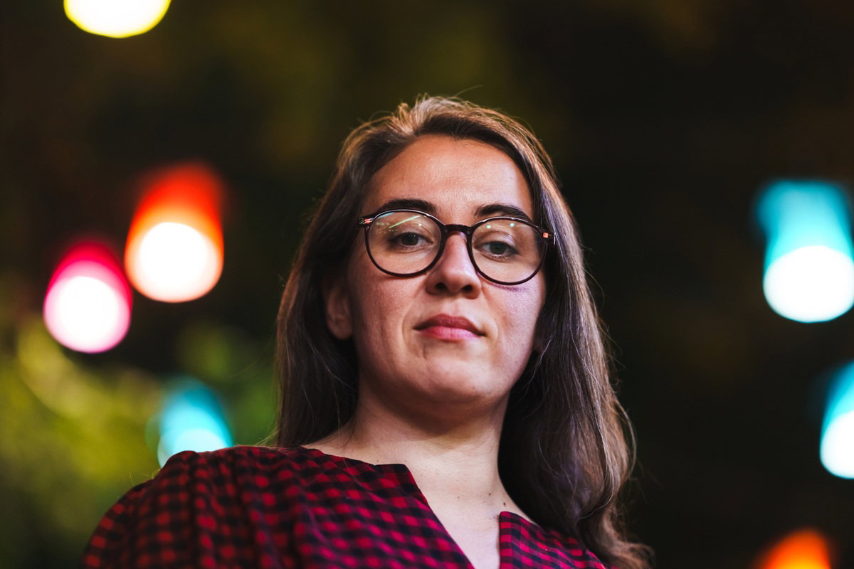 kobieta w wieku 35 plus w okularach patrzy niepewnie zamyślona stojąc na tle kolorowych świateł