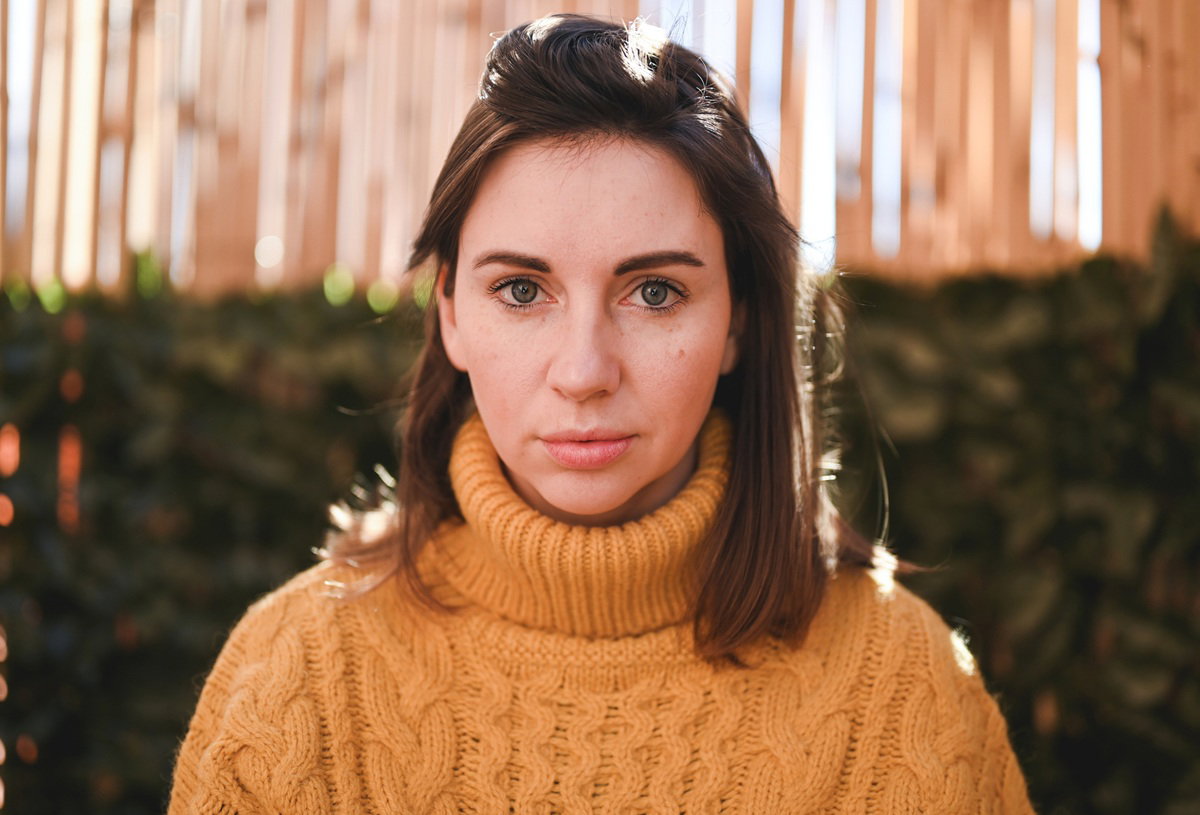 kobieta w wieku 25 plus w żółtym swetrze z golfem stoi zamyślona i smutna na zewnątrz