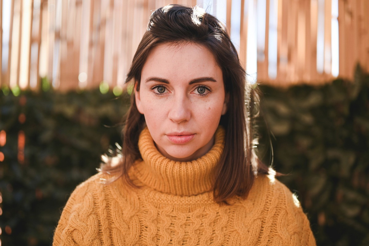 kobieta w wieku 25 plus w żółtym swetrze z golfem stoi zamyślona i smutna na zewnątrz