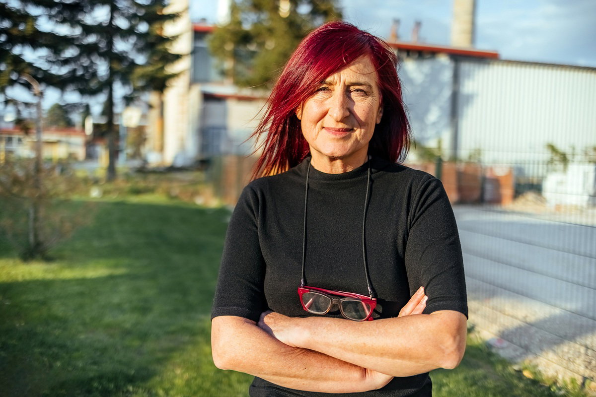 kobieta w wieku 55 plus w czarnej bluzce z włosami w intensywnym kolorze stoi poważna i zmartwiona