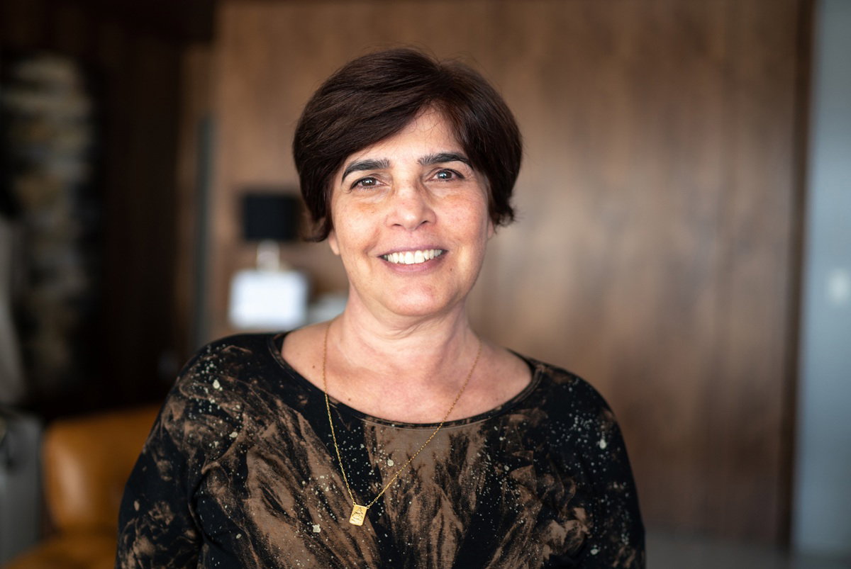 kobieta w wieku 60 plus z krótkimi włosami w ciemnej wzorzystej bluzce stoi w salonie i się uśmiecha