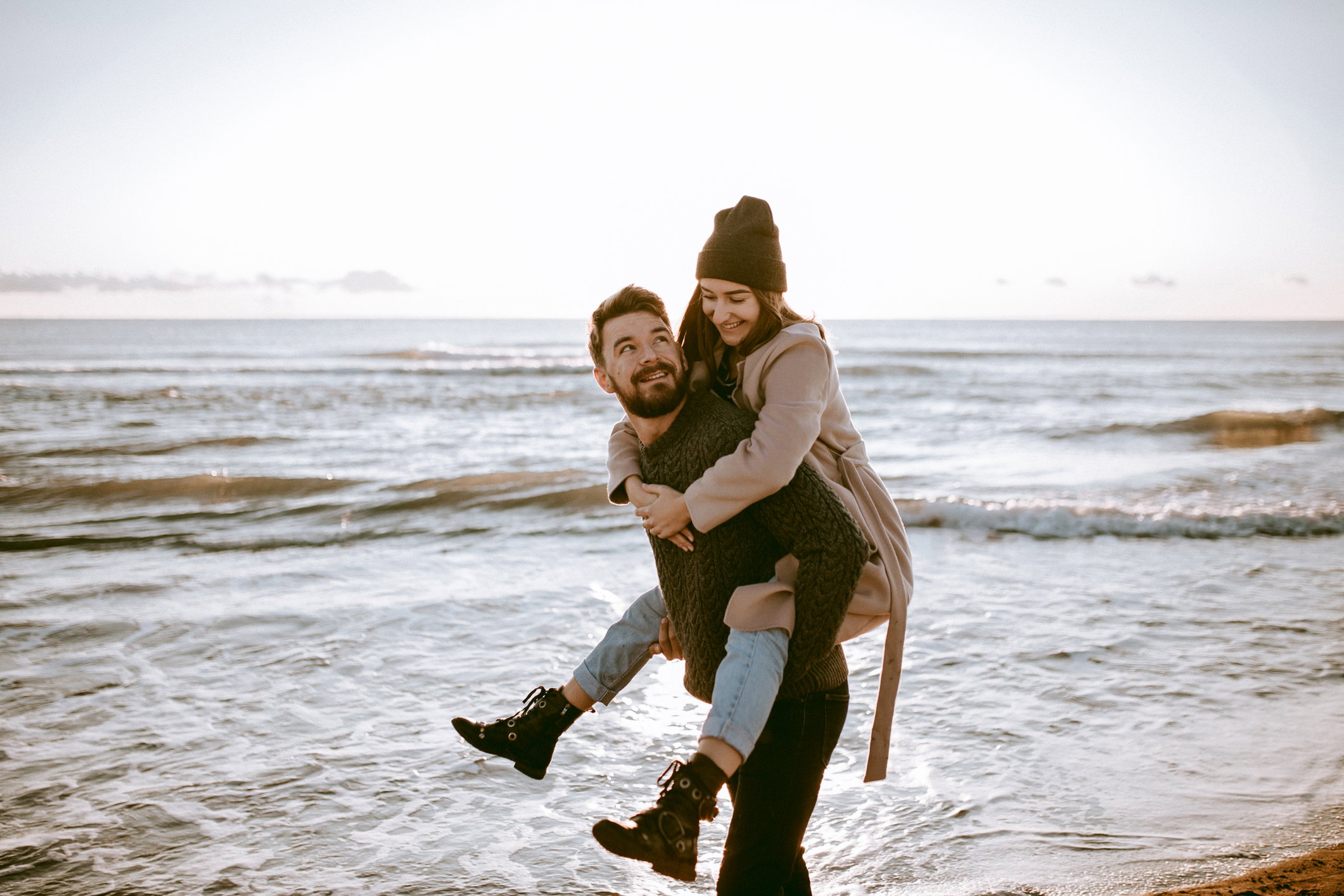 Piggyback couple at the beach celebrating their honeymoon at the winter time.