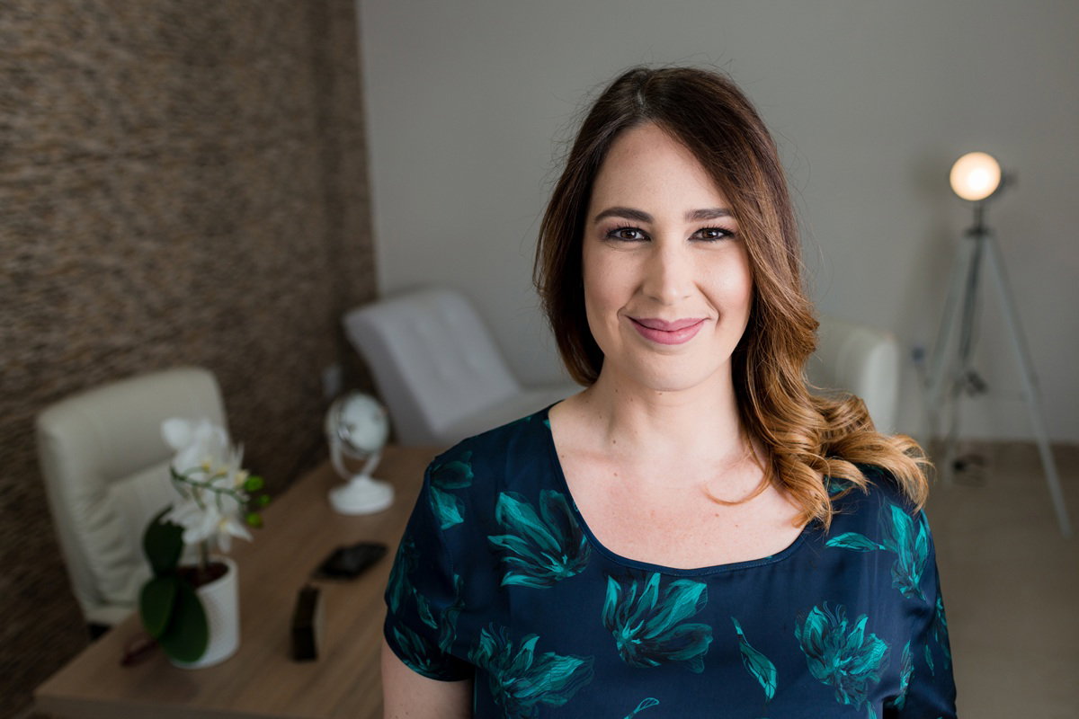 kobieta w wieku 35 plus w bluzce z roślinnym wzorem stoi w salonie i uśmiecha się kusząco