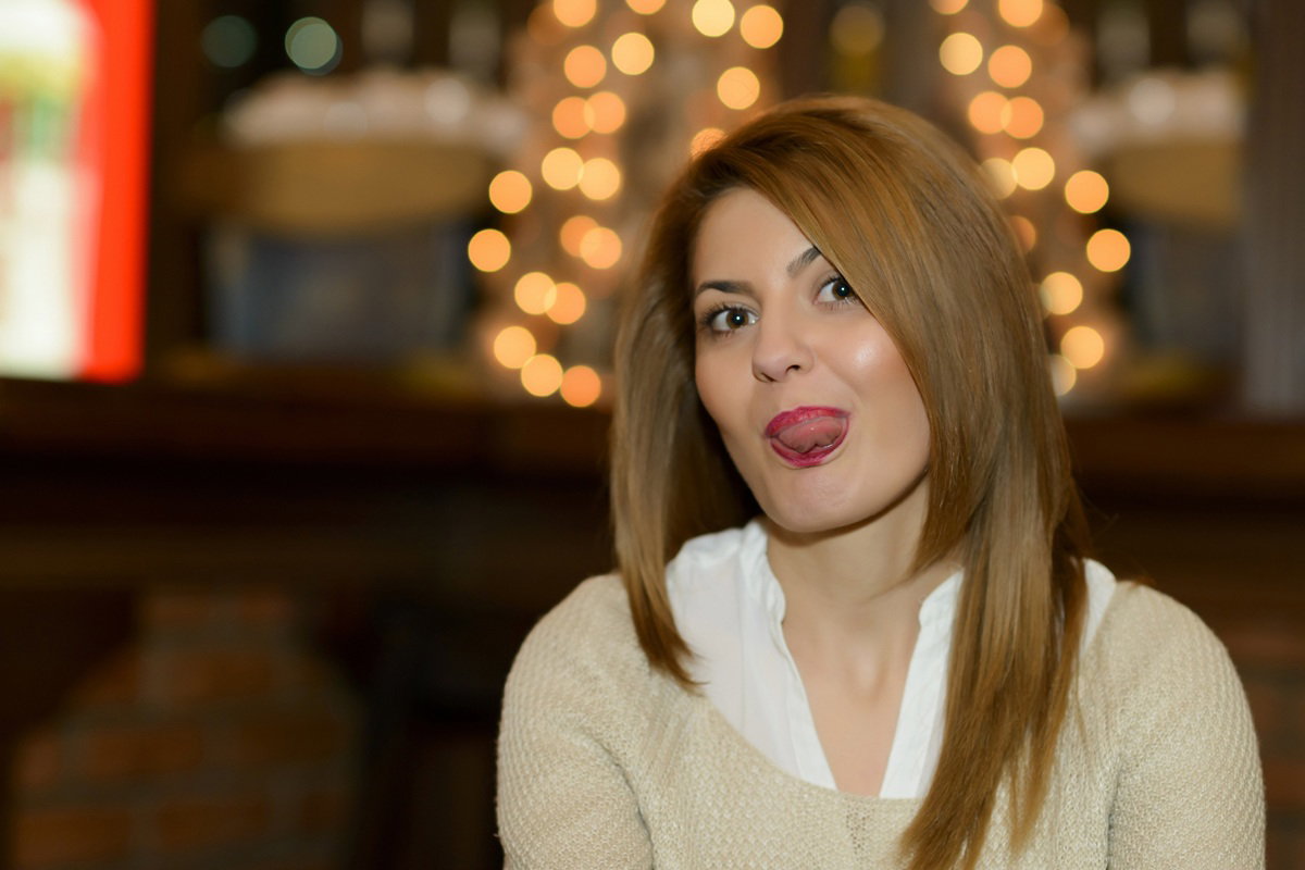 kobieta w wieku 30 plus długie włosy w jasnym sweterku pokazuje prowokująco język