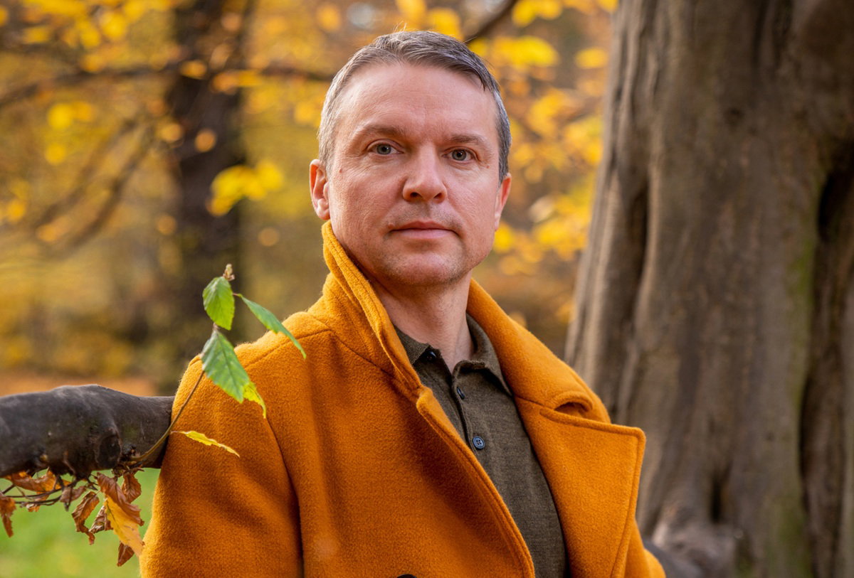Autumn photography. Beautiful colors of autumn. A man in a yellow coat and blue jeans near a tree. Yellow foliage. Calm. thoughtfulness. Reasoning. Dream. Loneliness.Autumn look