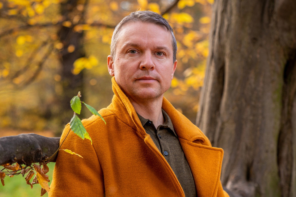 Autumn photography. Beautiful colors of autumn. A man in a yellow coat and blue jeans near a tree. Yellow foliage. Calm. thoughtfulness. Reasoning. Dream. Loneliness.Autumn look