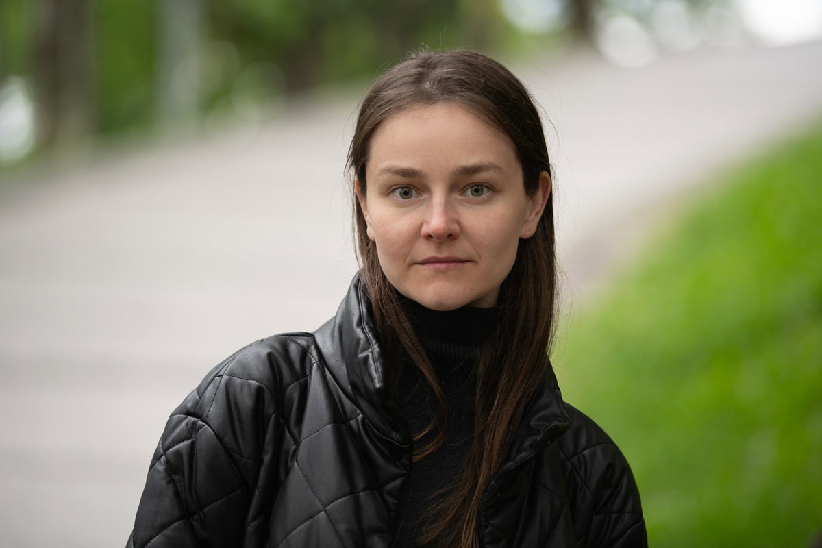 kobieta w wieku 30 plus w czarnej kurtce stoi na zewnątrz zamyślona i zawiedziona życiem