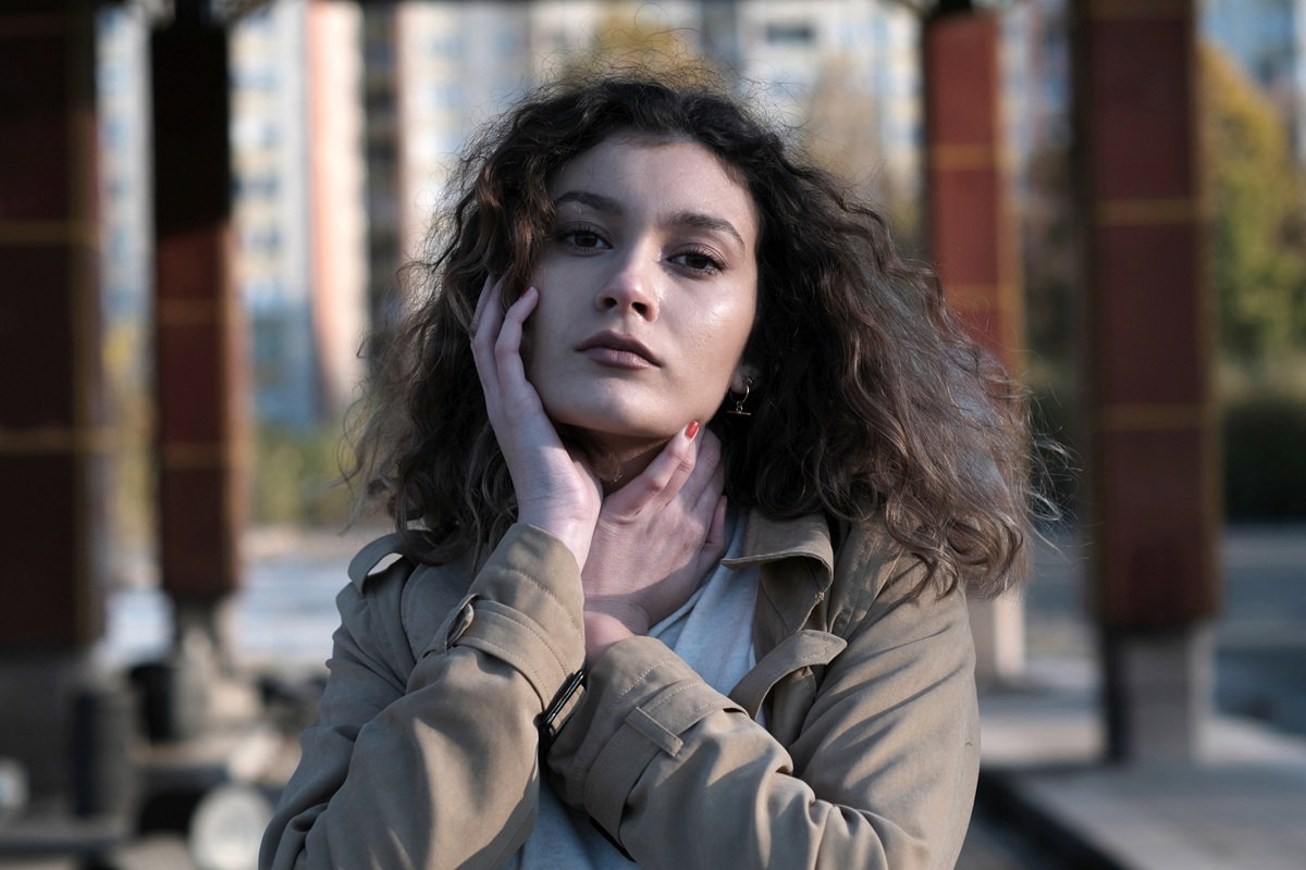 kobieta w wieku 25 plus z długimi pofalowanymi włosami rozemocjonowana stoi na osiedlu