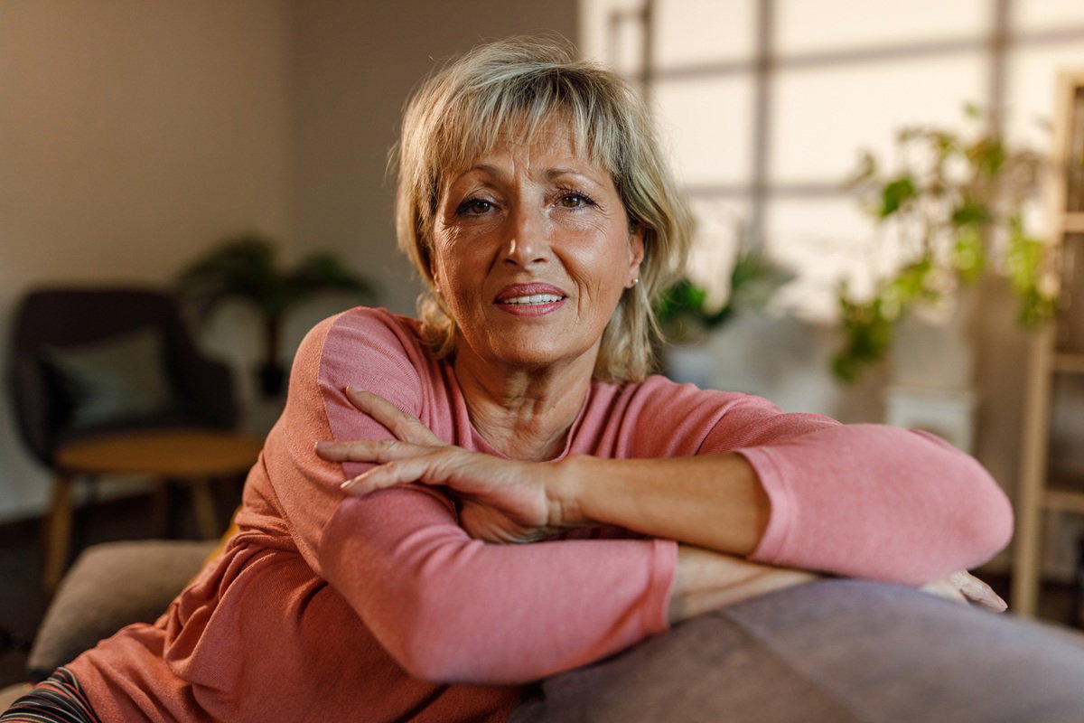 kobieta w wieku 60 plus blondynka siedzi na kanapie lekko zmartwiona