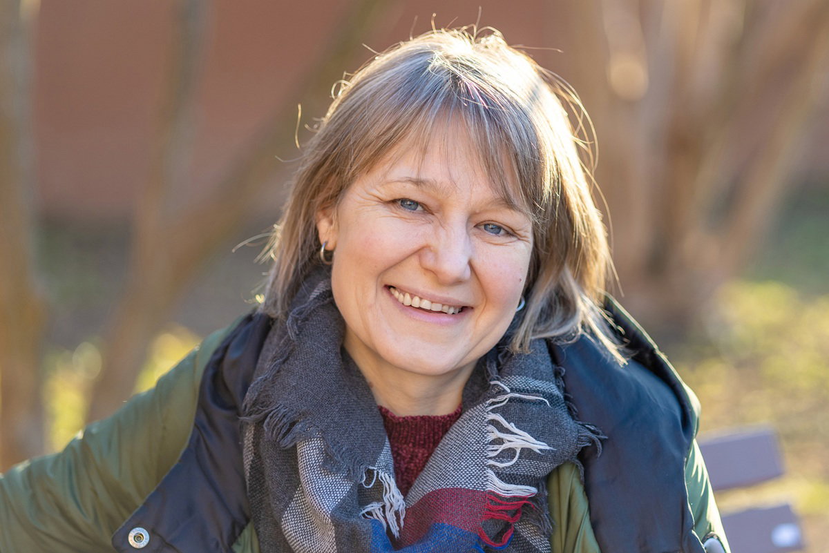 kobieta w wieku 40 plus stoi w szalu na zewnątrz i się uśmiecha