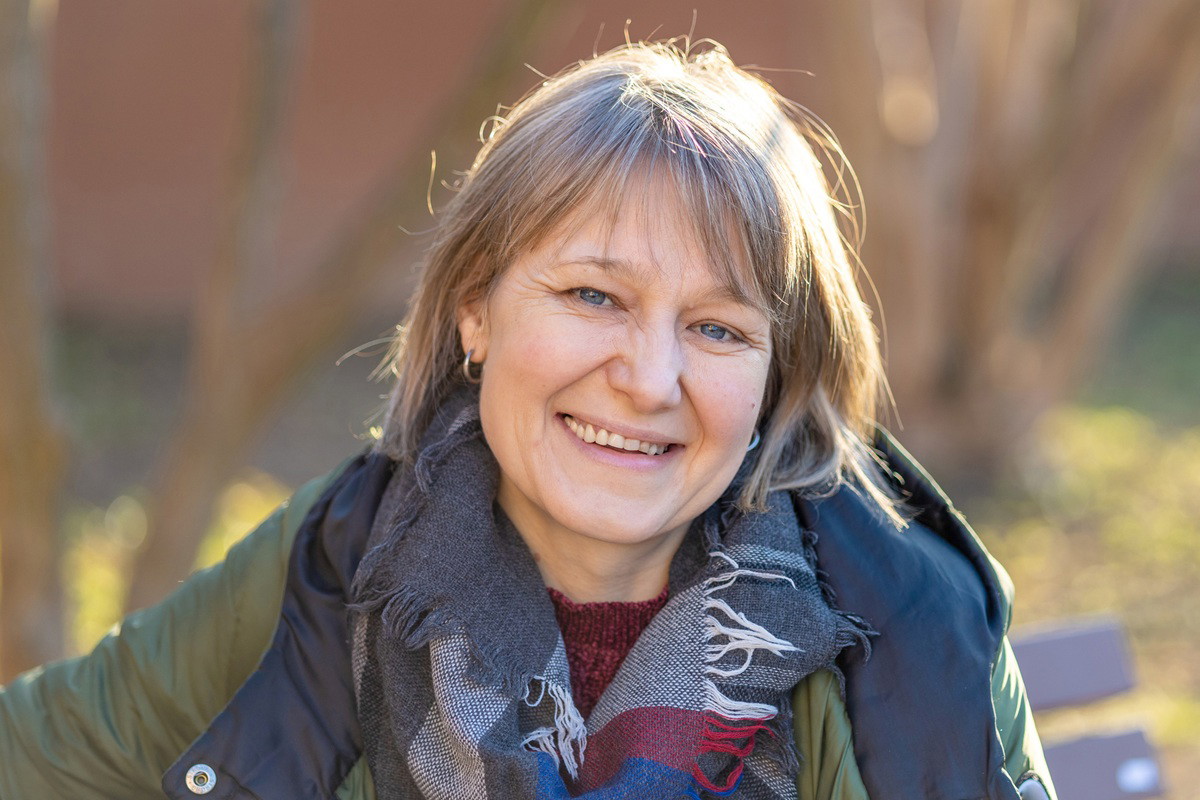 kobieta w wieku 40 plus stoi w szalu na zewnątrz i się uśmiecha