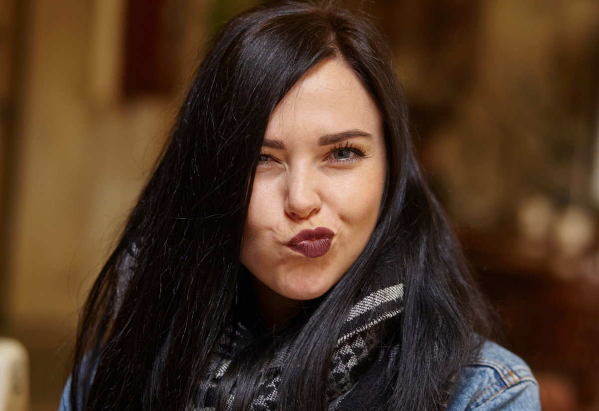 kobieta w wieku 30 plus z ciemnymi włosami robi zabawną minkę i jest zadowolona